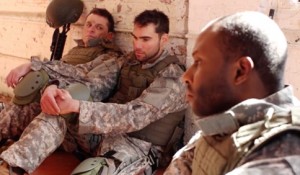 Three men in camouflage uniforms sitting next to each other.