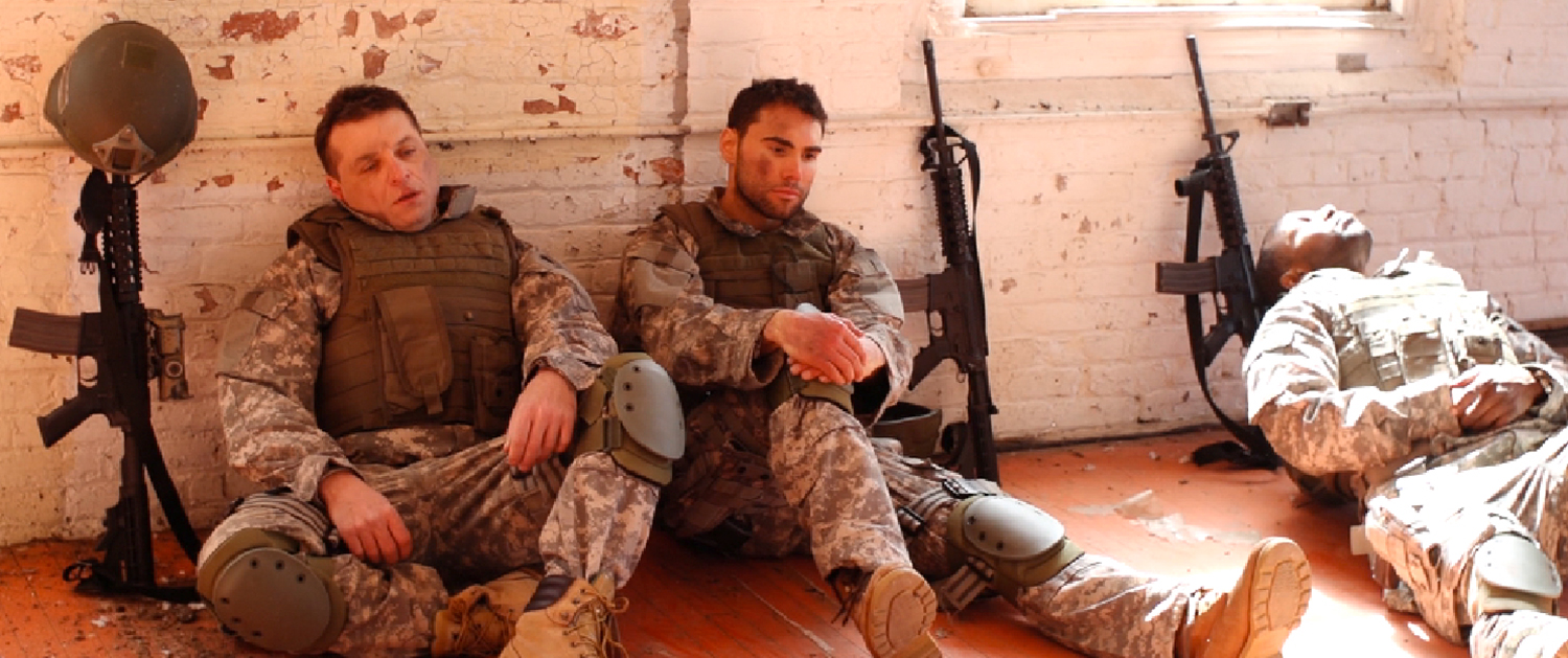 A man in military fatigues sitting on the ground.