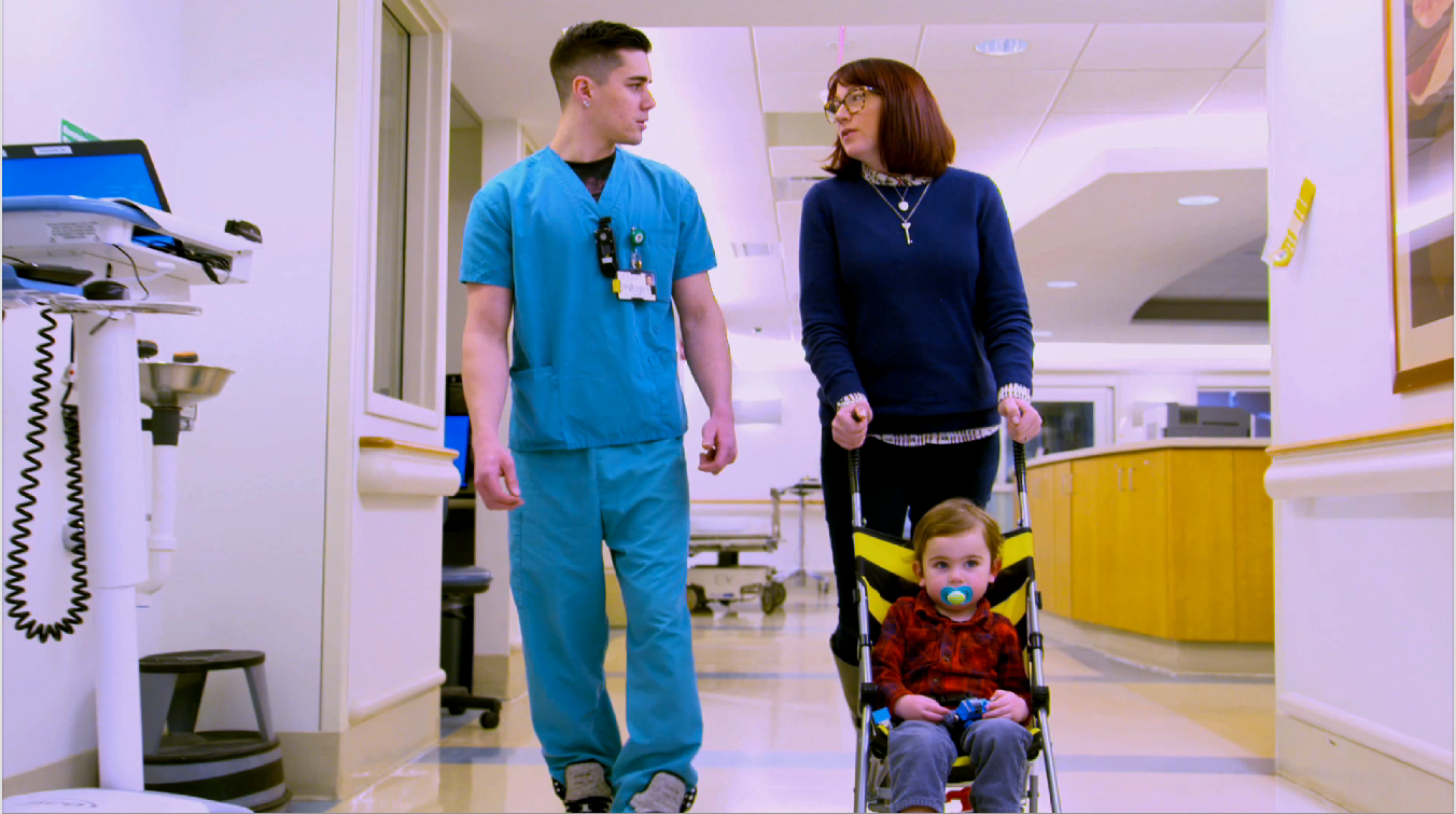 A woman and two men walking down the hallway of a hospital.
